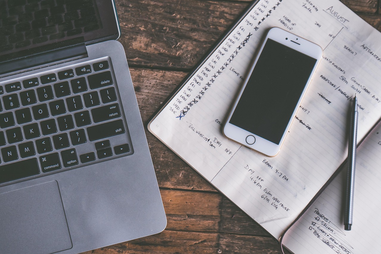 Laptop, smartfon i notes z zapisanym planem na drewnianym biurku